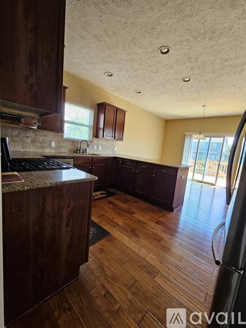 A kitchen with wooden cabinets and a black refrigerator.