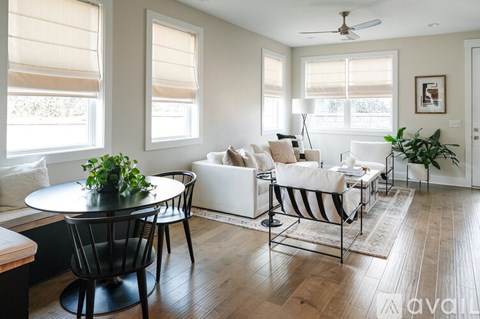 A living room with a white couch, a black chair, and a small table with a potted plant on it.