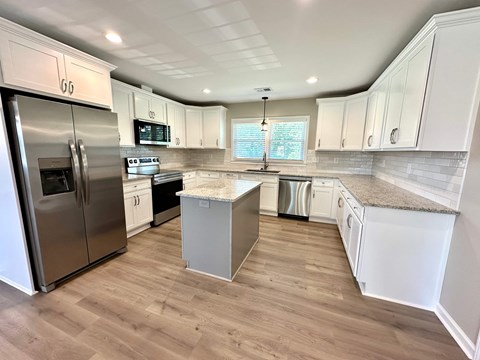 A kitchen with white cabinets and a stainless steel refrigerator.
