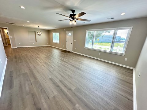 A spacious room with a ceiling fan and wooden flooring.