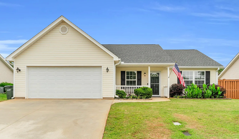 A house with a garage and an American flag on the front porch.