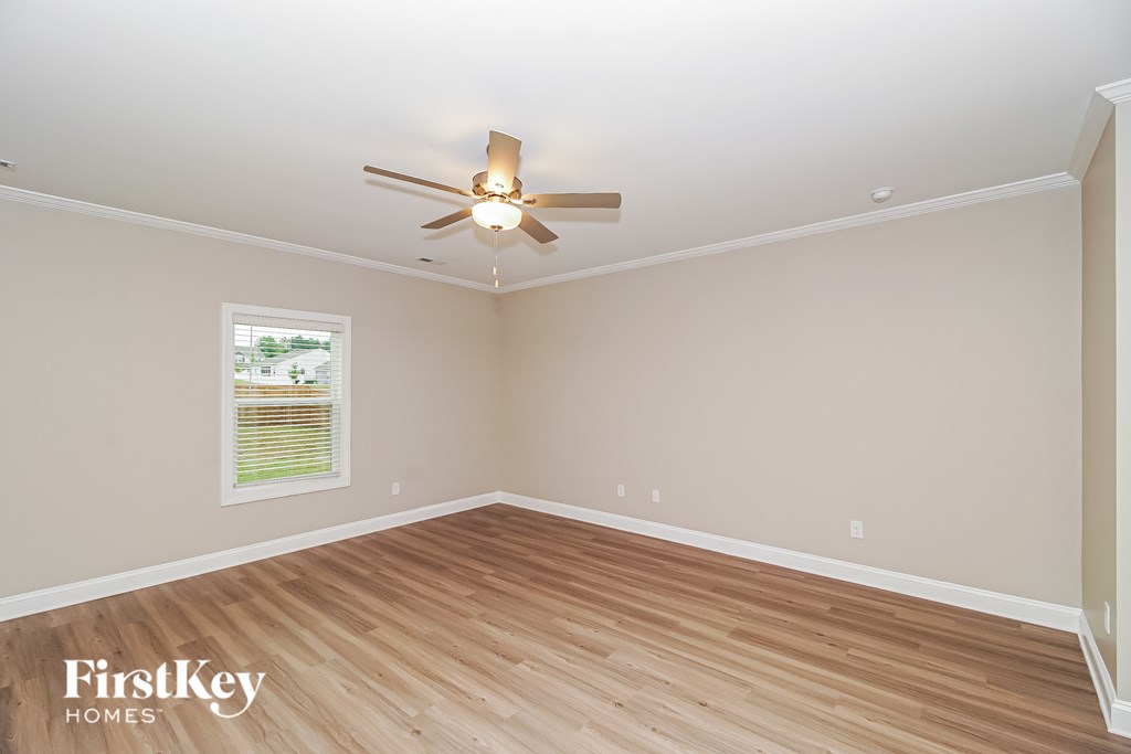 A room with a ceiling fan and wooden flooring.