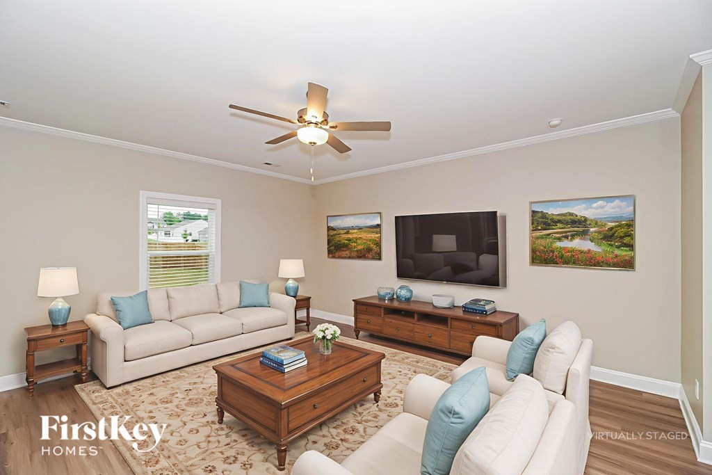 A living room with a beige couch, a wooden coffee table, and a ceiling fan.