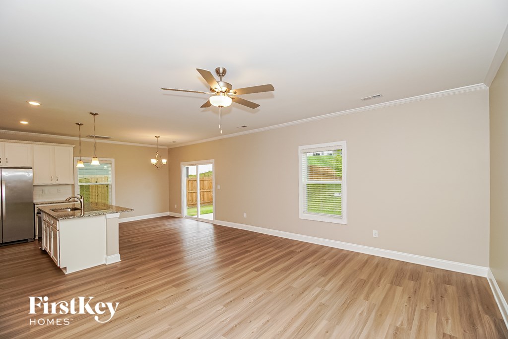 A spacious room with wooden floors and a ceiling fan.