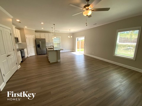 A spacious kitchen and living room with wooden floors and a ceiling fan.