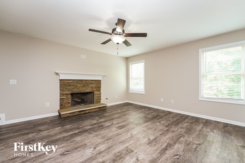 A spacious room with a fireplace and a ceiling fan.