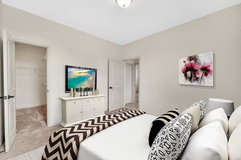 A living room with a white couch and a television on a white cabinet.