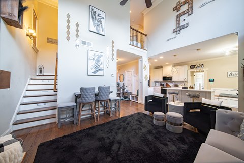 A living room with a black rug and a staircase.
