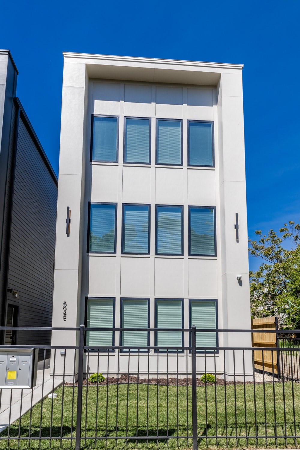 A modern building with a white facade and black fence.