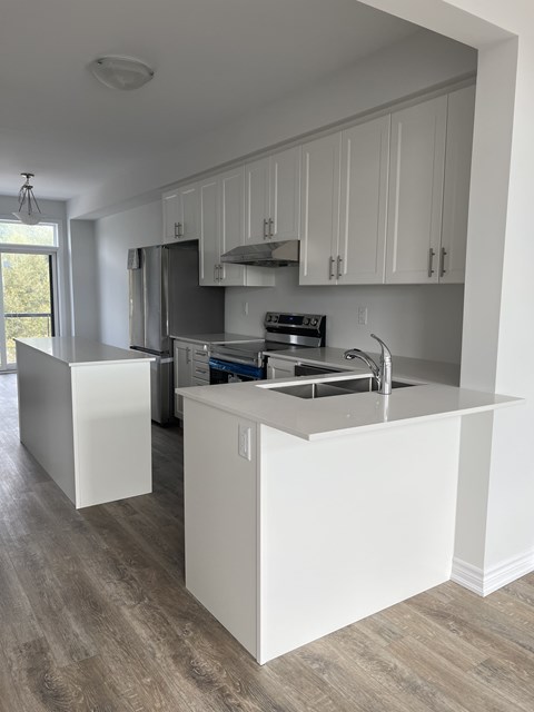 A kitchen with white cabinets and a wooden floor.