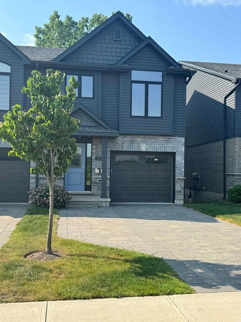 A house with a grey garage door and a tree in front.