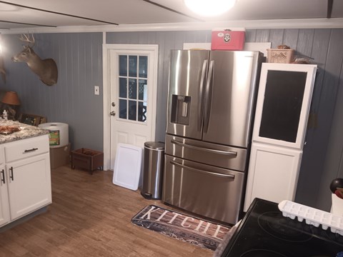 A kitchen with a stainless steel refrigerator and a black stove top.