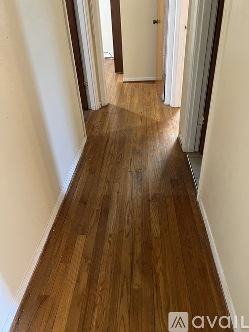A hallway with wooden floors and white walls.