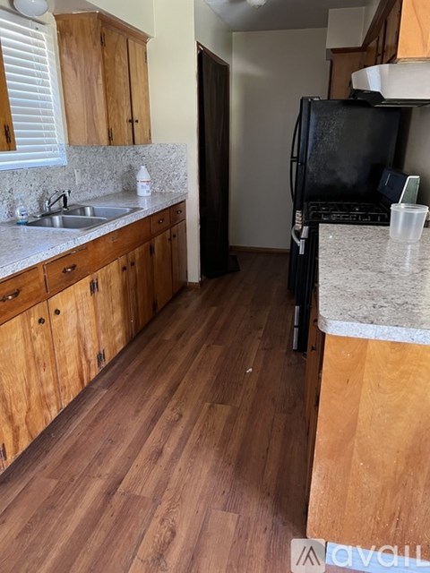 A kitchen with wooden cabinets and a black fridge.