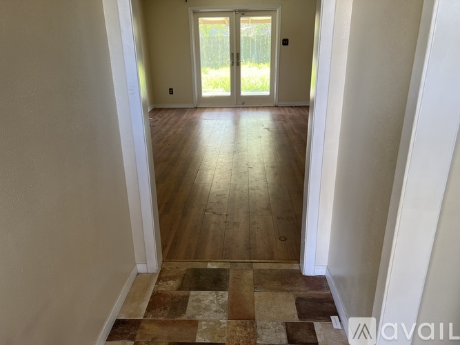 A hallway with a tiled floor and a door at the end.