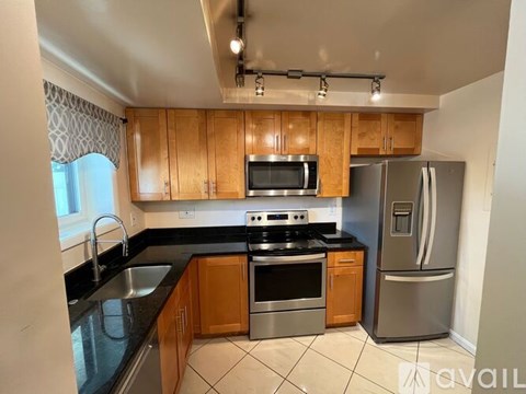A kitchen with wooden cabinets and black countertops.