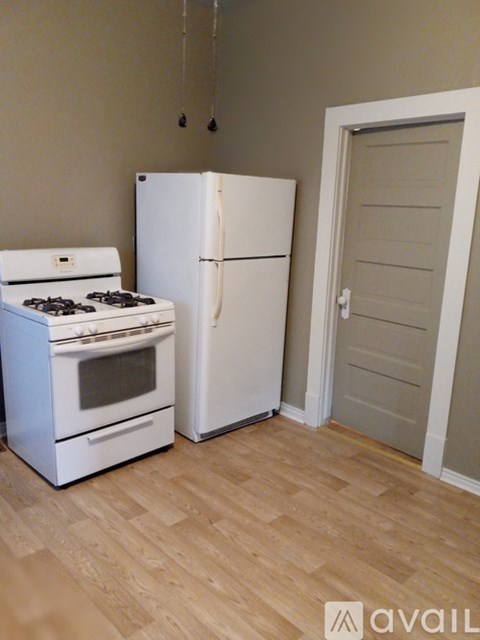 A kitchen with a white stove and refrigerator in it.