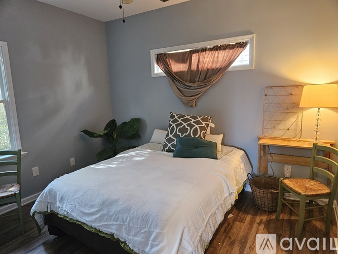 A bedroom with a bed, desk, chair, and window.