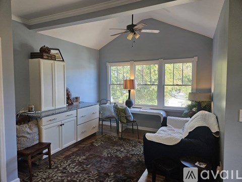 A living room with a black couch and a fan.