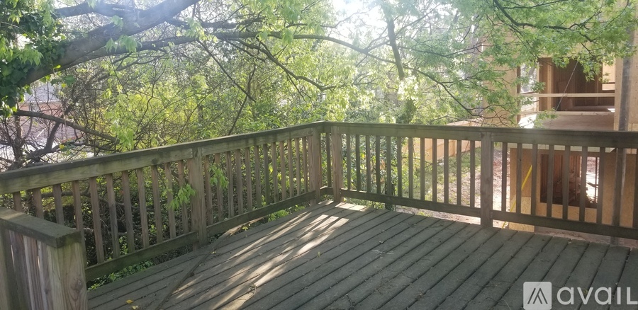 A wooden deck with a railing and trees in the background.