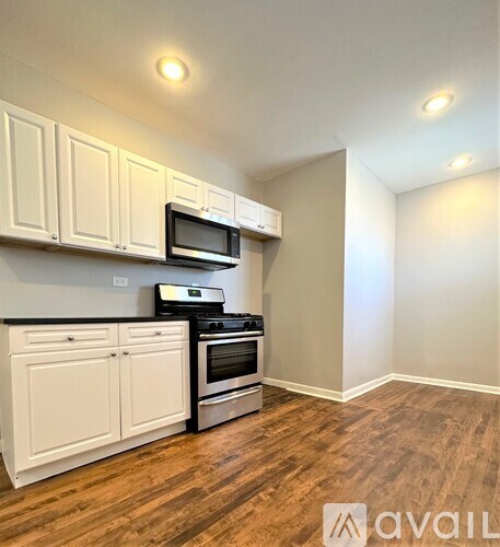 A kitchen with white cabinets and a wooden floor.