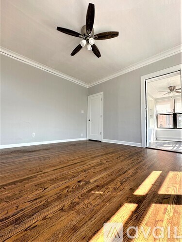 A room with a ceiling fan and wooden flooring.
