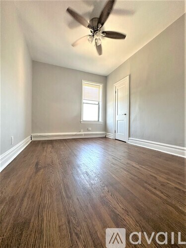 A room with wooden flooring and a ceiling fan.