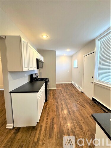 A kitchen with white cabinets and a black countertop.