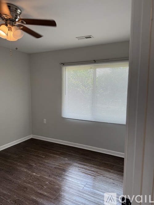 A room with a ceiling fan and a window with blinds.