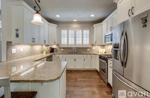 A kitchen with a granite countertop and stainless steel appliances.
