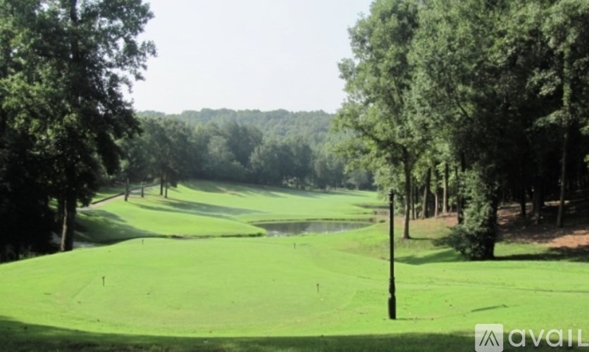 A golf course with a green and trees in the background.