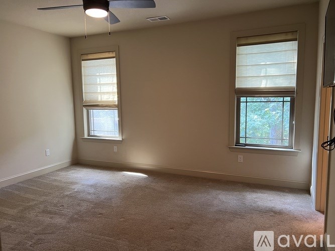 A room with a carpeted floor and two windows.