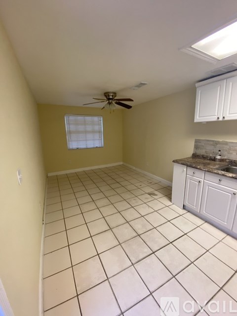 A kitchen with white cabinets and a ceiling fan.