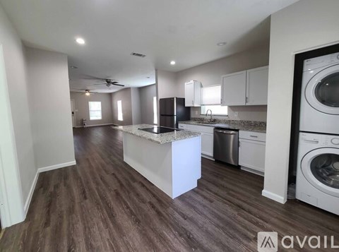 A spacious kitchen with dark wood floors and white appliances.