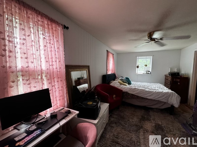 A room with a bed, a desk with a computer, and a chair.