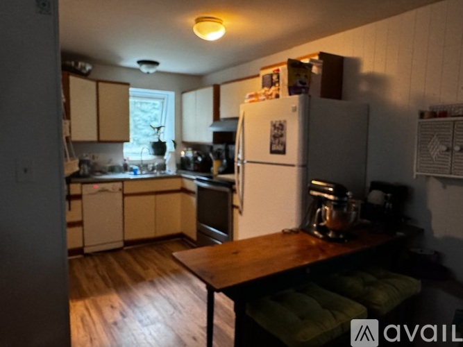A kitchen with a refrigerator, a table, and a window.