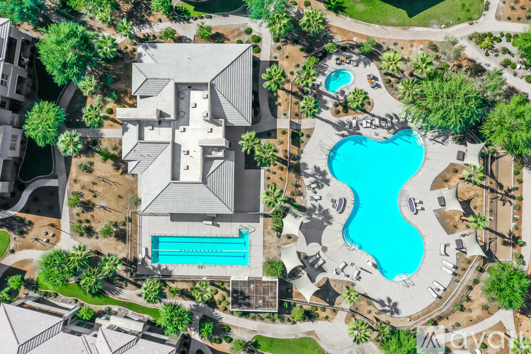 An aerial view of a resort with a large swimming pool and a building.