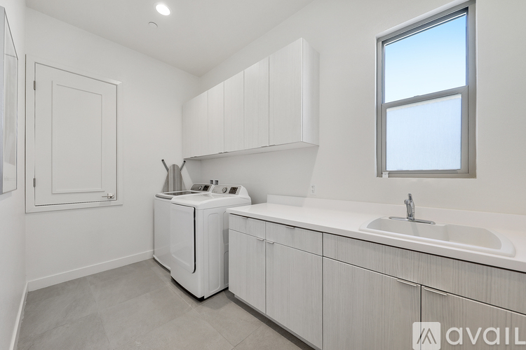 A small, modern kitchen with white cabinets and a washer and dryer built in.