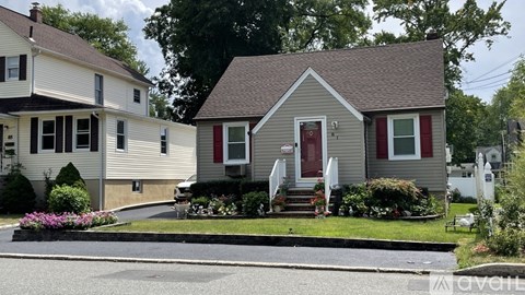 A house with a red door is in front of a white house.