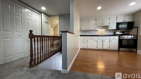 A kitchen with white cabinets and a wooden staircase.