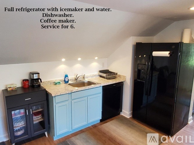 A kitchen with a black fridge, a sink, and a coffee maker.