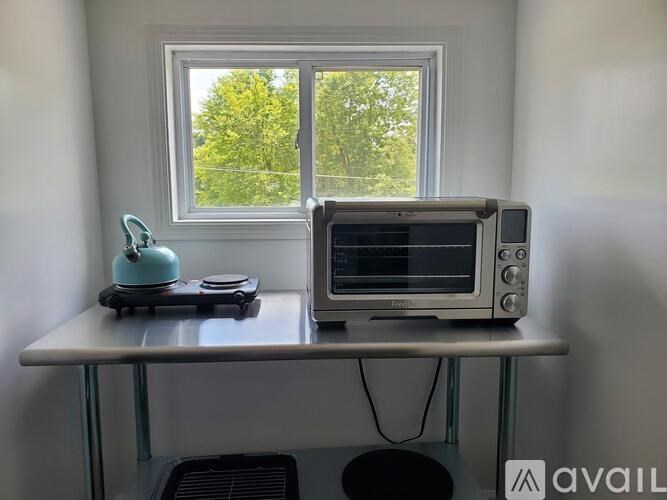 A silver toaster oven is on a table next to a window.