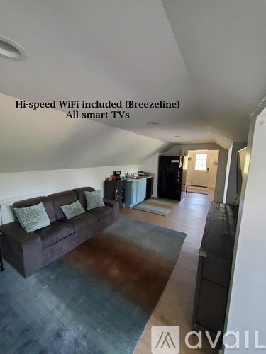 A living room with a couch and a note that says "Hi-speed WiFi included (Breezeline) All smart TVs".