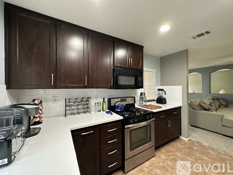 A kitchen with dark brown cabinets and white countertops.
