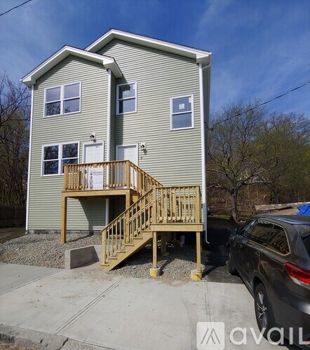 A two-story house with a wooden deck and stairs.