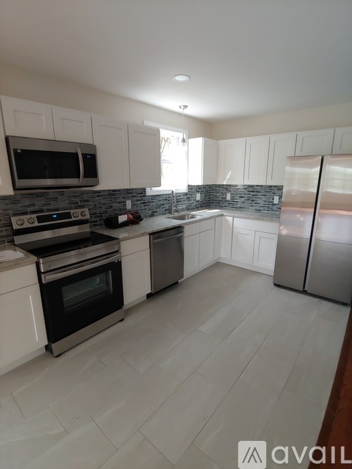 A kitchen with white cabinets and a tiled backsplash.