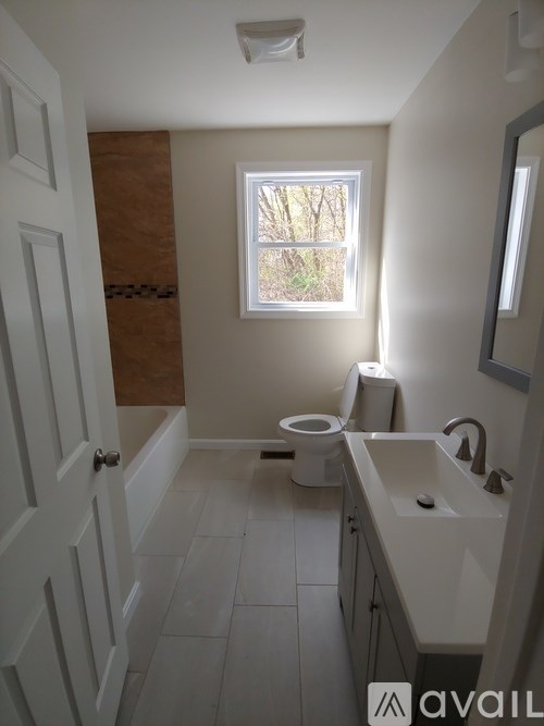 A bathroom with a toilet, sink, and a window.
