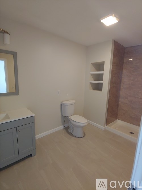 A bathroom with a toilet, sink, and wooden floors.