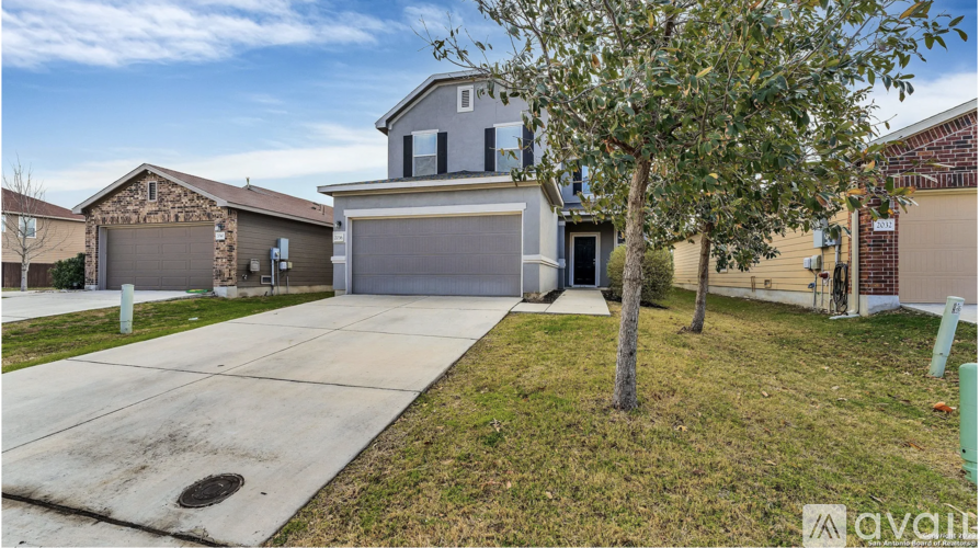 A house with a garage and a tree in front.