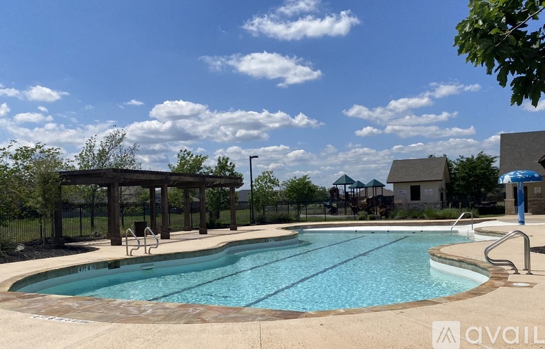 A large outdoor swimming pool with a pavilion and a small building in the background.